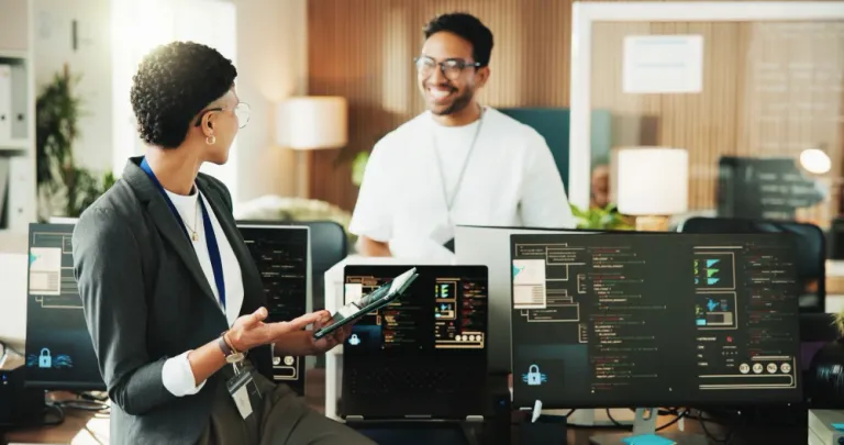 Technology professionals collaborating in a modern office with software code displayed on multiple monitors, representing offshore vendor governance and development team oversight.